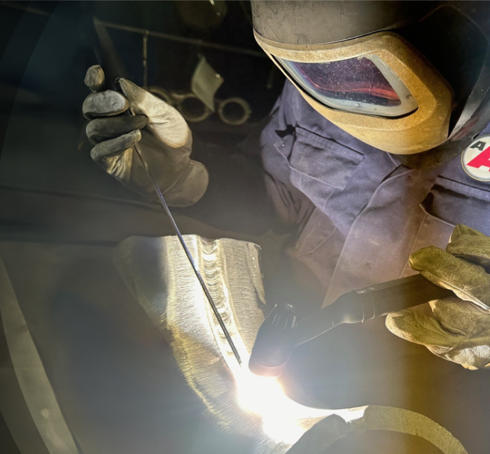 A man wearing a welding helmet engaged in welding
