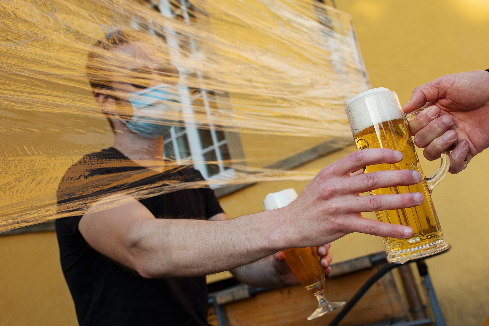 Student Moritz, mit Sonnenbrille, Mundschutz und Frischhaltefolienspuckschutz vor Gefahren geschützt, verkauf am 27.04.2020, in Zeiten der Coronavirus-Pandemie, Bier am Außer-Haus-Verkauf des Unikellers am Schloss in Osnabrück. Foto: David Ebener ***Stichworte*** Symbolbild, Symbolfoto, Illustration, Unikeller, Uni-Keller, Biergarten, Biergärten, Kneipe, Außer Haus, Verkauf, Coronavirus, Corona-Virus, Corona Virus, Corona-Virus-Pandemie, SARS-CoV2, COVID-19, Krankheit, Krankheiten, Pandemie, Lungenkrankheit