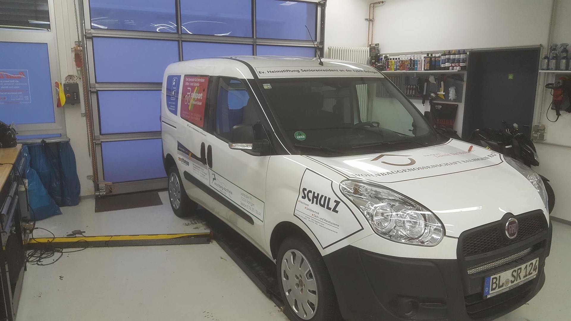 Fiat Doblo mit Fahrzeugbeschriftung und Werbung für eine Wohnbaugenossenschaft.