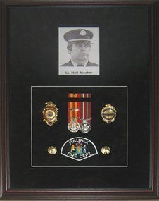 Medals, uniform badges, buttons and photo of firefighter framed in a mahogany shadow box with black suede mats