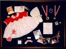 Items from birth to adulthood shadow box Baby's dress, bonnet, shoes,  sports awards, photos from birth to adult framed in a mahogany shadow box with blue suede mats