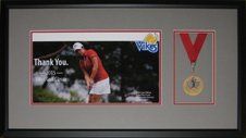 Photo and gold medal from the 2015 Canadian University/College Golf Tournament framed in a black shadow box with grey and red mats
