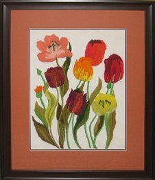 Crewel of tulips and poppies framed in a brown frame with orange and brown mats