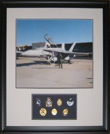 Photo of CF18 fighter jet, medallions and cap badges framed in a black shadow box with grey and blue mats