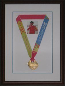 Photo and gold medal from 2011 Pan Am Games in Men's  K-2 200m framed in a brown shadow box with white and blue mats