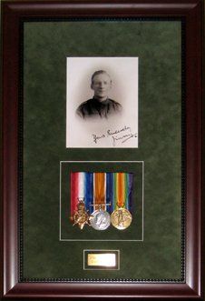 Portrait photo, medals and engraved nameplate framed in a mahogany shadow box with green suede mats