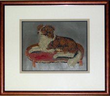 Needlepoint of a dog on a cushion framed in a brown beaded frame with cream, taupe, and brown mats