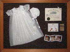 Christening gown, birth certificate, and baby photos shadow box Christening gown, birth certificate, baby photos framed in a teak colour shadow box with brown suede mats