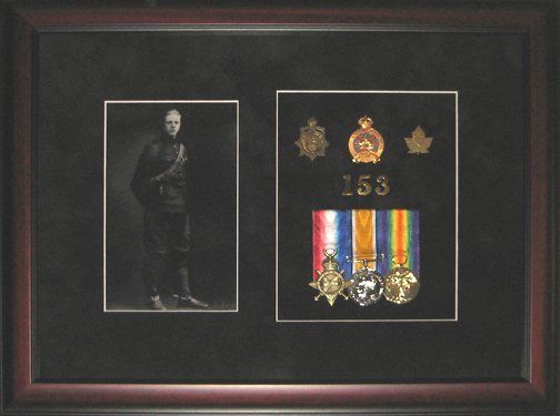 Shadow box with grandfather's military memorabilia Portrait photo, cap badges, pins, and medals framed in a mahogany shadow box with black suede mats
