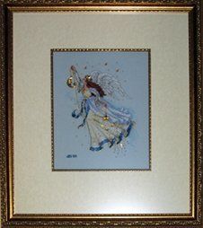Cross-stitch of an angel holding a gold moon charm framed in a gold ornate frame and fillet with parchment mat