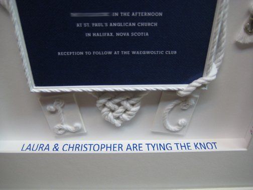 A nautical themed wedding invitation is framed in rustic style white frame with rope design elements