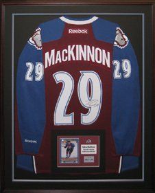 Autographed Nathan Mackinnon hockey jersey, hockey card and pin framed in a  mahogany shadow box with black and blue mats