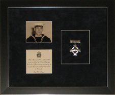 Portrait photo and Memorial Cross with accompanied note framed in a black with silver pinstripes shadow box and black suede mats