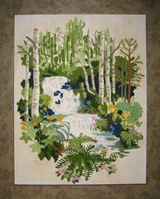 Crewel of a summer forest scene framed in a taupe burl frame