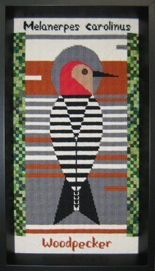 Needlepoint of a woodpecker framed in a black bevel frame