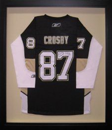 Signed junior size Sidney Crosby hockey jersey in a black shadow box with golden tan mats