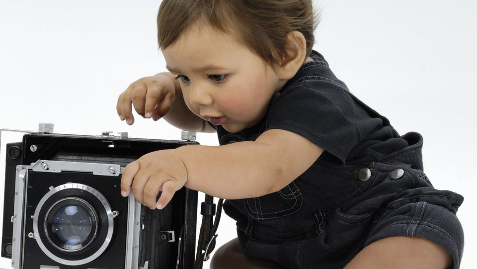 Ein Kleinkind erkundet einen antiken Fotoapparat