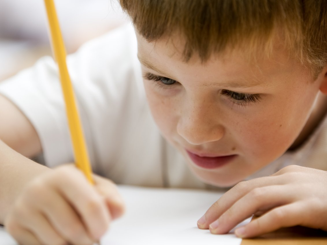 Ein Junge schreibt in der Schule etwas auf ein Blatt