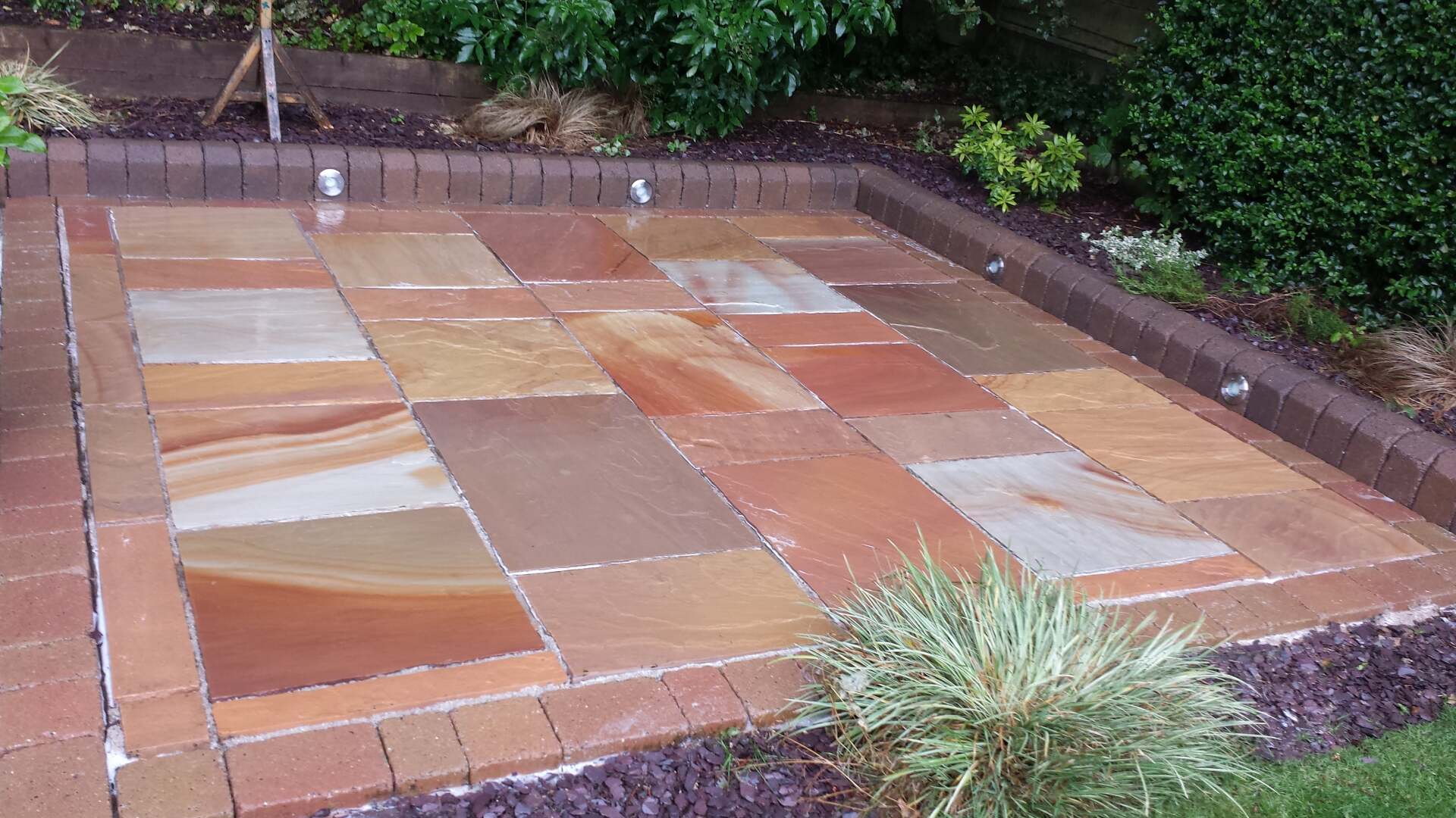 Dirty lichen infested Indian sandstone patio after cleaning