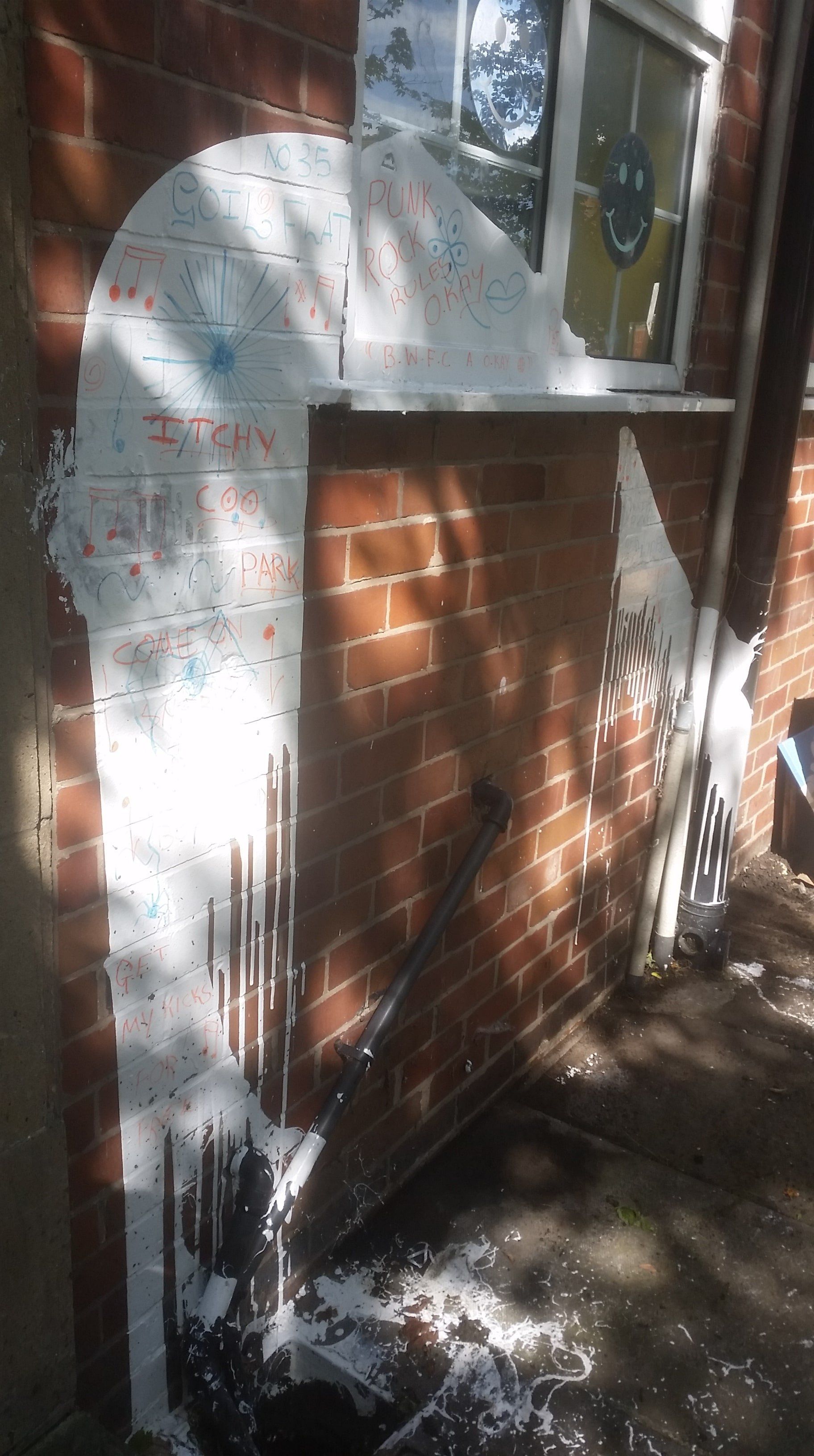 Brick wall with spilt paint and graffiti before cleaning