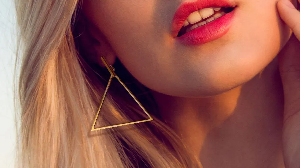 Blonde Frau mit roten Lippen trägt Dreieckige Ohrringe