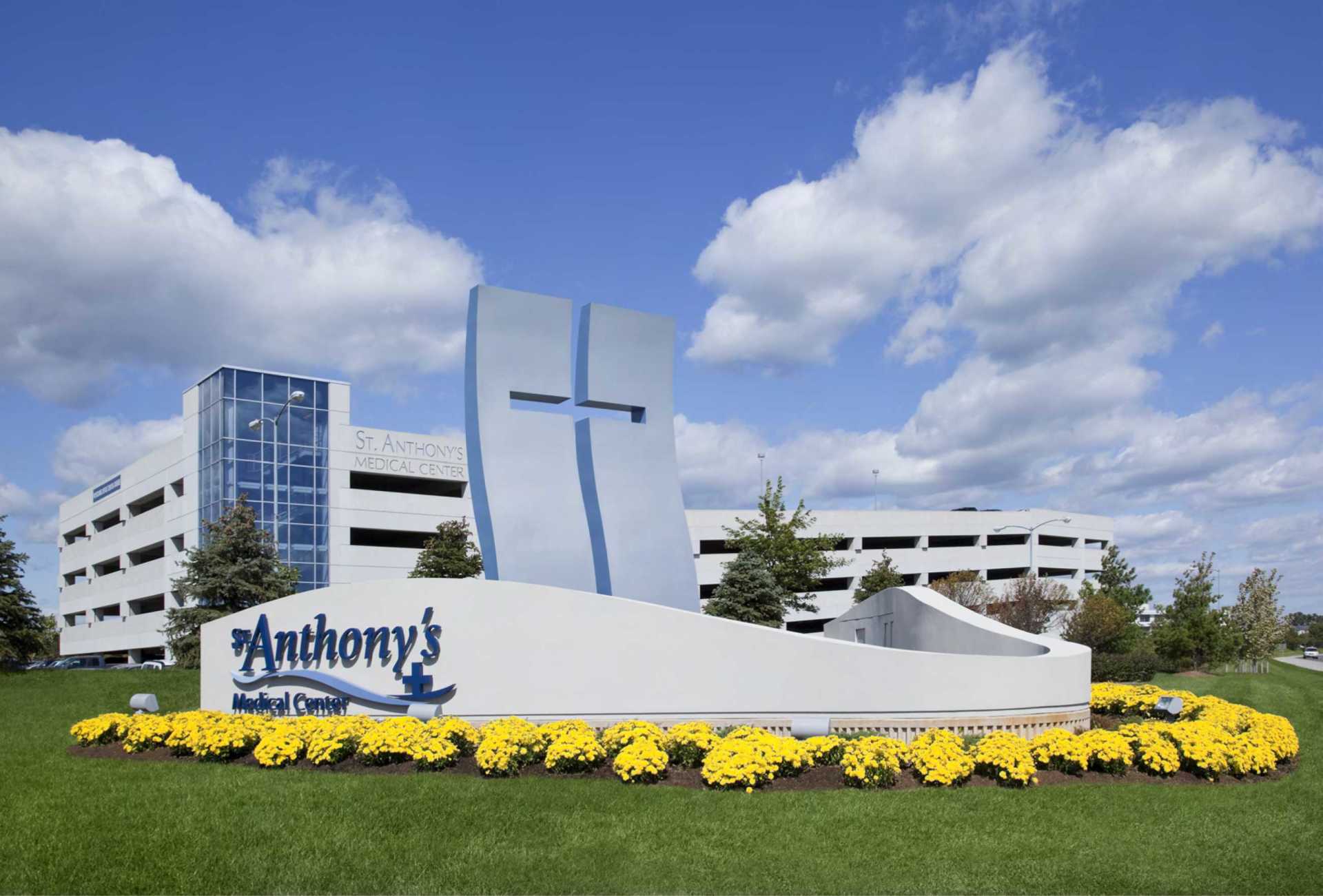ENHANCED STREETSCAPE ELEMENTS INCLUDE A MAJOR SITE IDENTIFICATION SIGN AS WELL AS A STYLIZED 40' TALL SCULPTURAL CROSS TO EMPHASISE THE FAITH BASED CONNECTION OF THIS HOSPITAL LIGHTING INCLUDED BACK LIGTHED LETTERS AND LOGO WITH FLOOD LIGHTING ON THE ENTIRE FEATURE