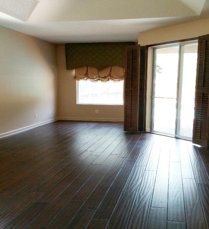 Dark wood plank flooring and window treatments with carved cornice board and blue silk shade.