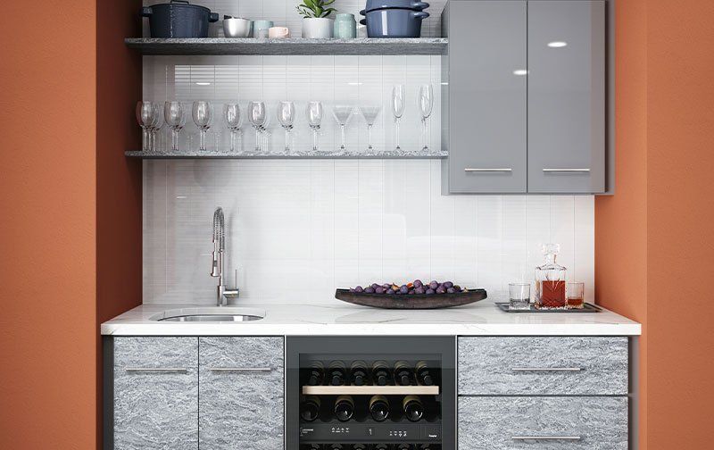 Ideal Cabinetry clean and contemporary wet bar with flat panel cabinets in gray and marbled tones.