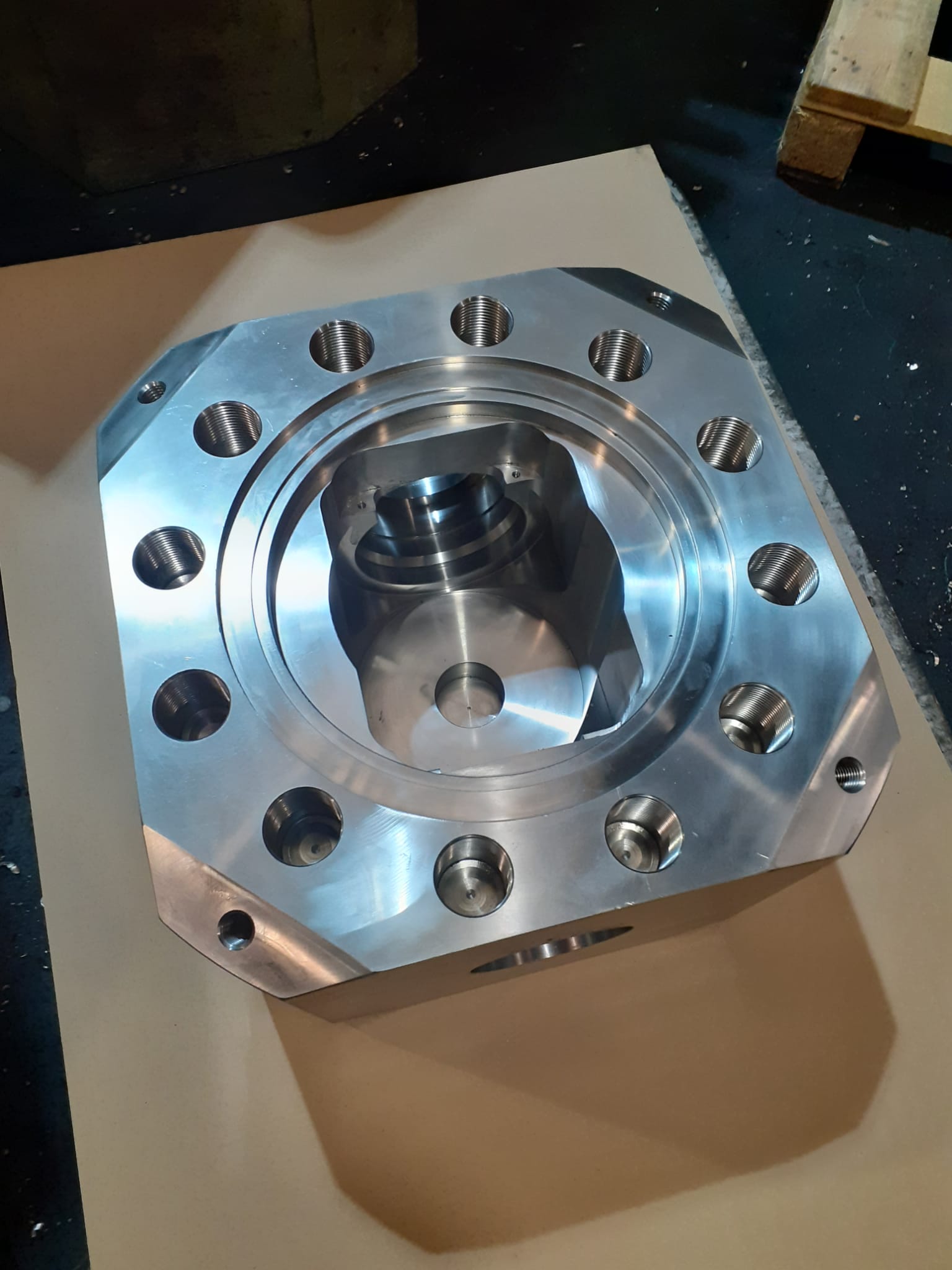 Bloque de aluminio mecanizado en CNC con múltiples orificios roscados y cavidad interior, componente industrial de alta precisión.