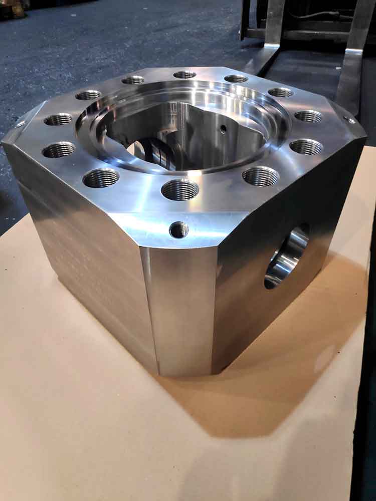 Bloque metálico mecanizado en CNC con orificios roscados y cavidad central, pieza industrial de alta precisión para maquinaria o sistemas hidráulicos.