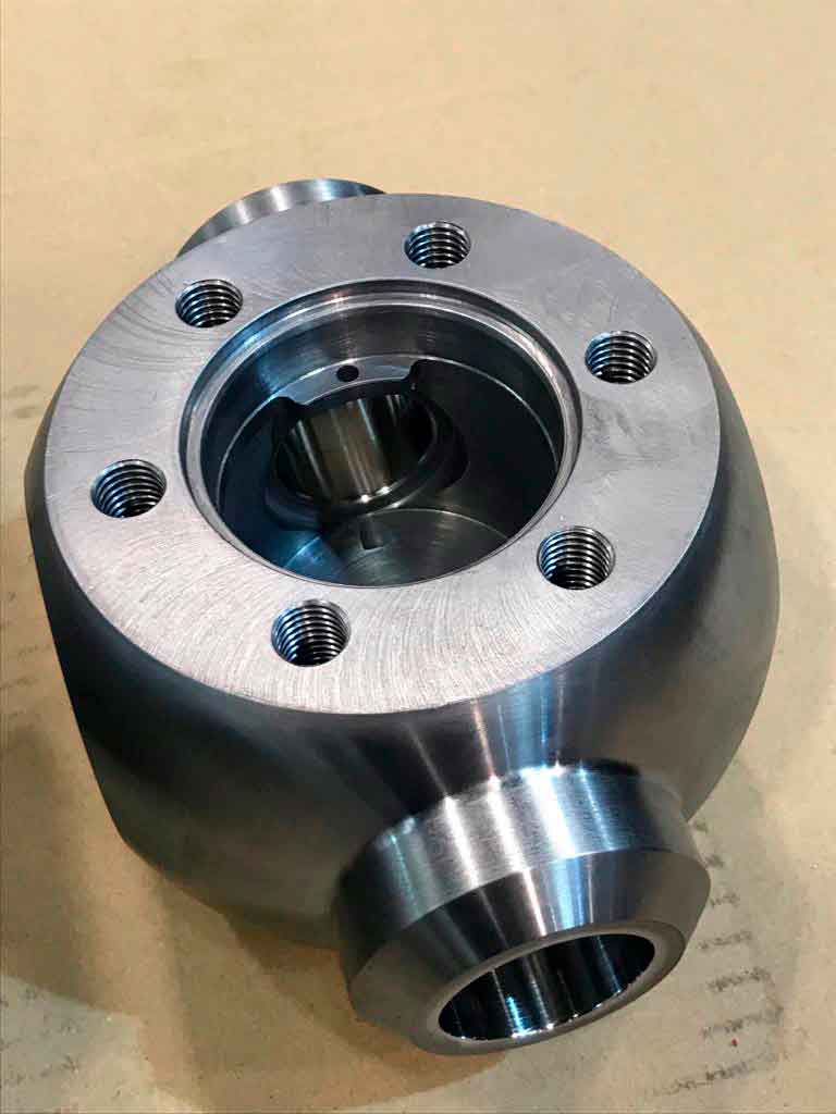 Cuerpo metálico mecanizado en CNC con orificios roscados y alojamiento interior, componente industrial de alta precisión.
