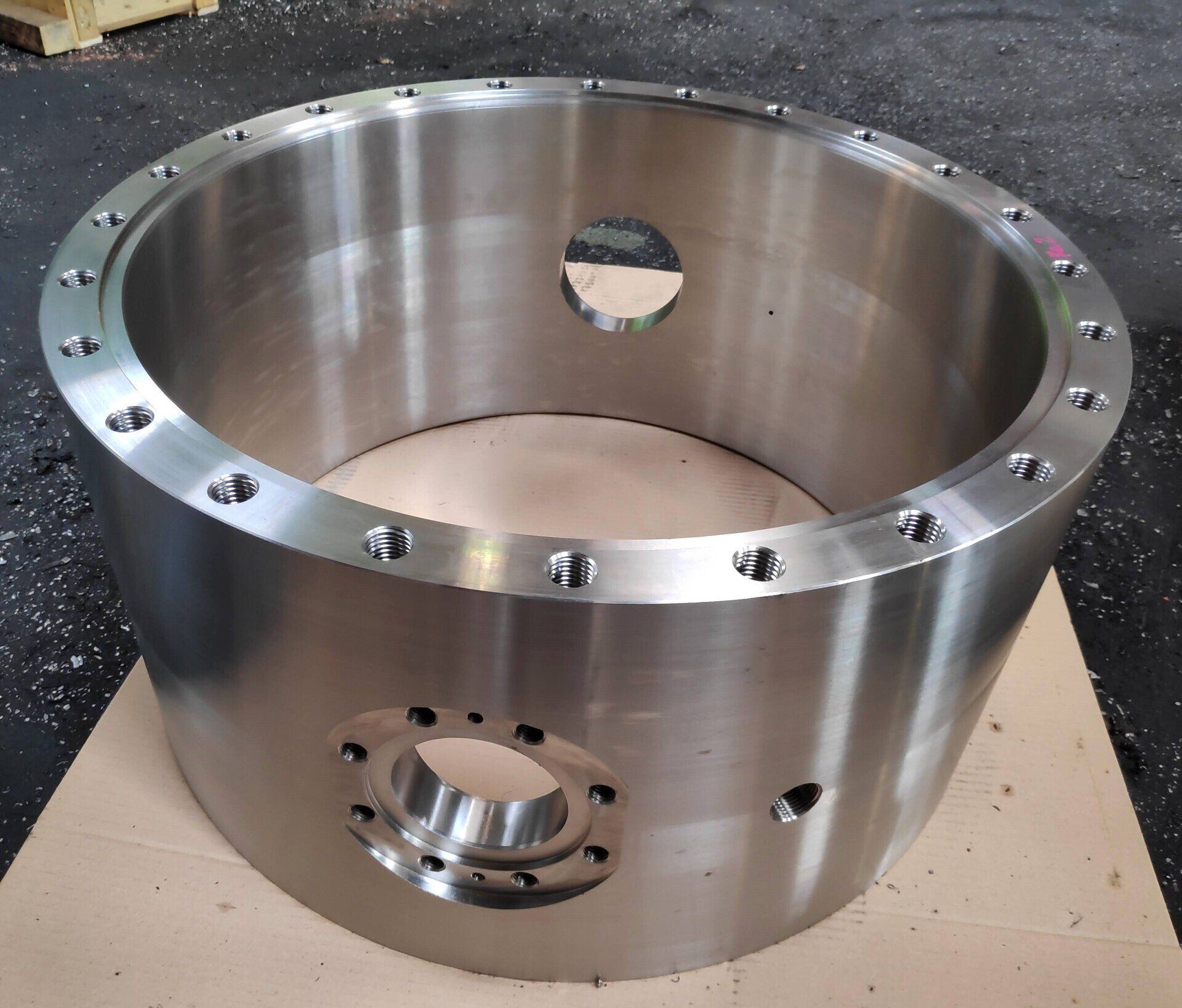 Carcasa industrial de gran diámetro mecanizada en CNC con taladros roscados y alojamiento lateral de precisión.