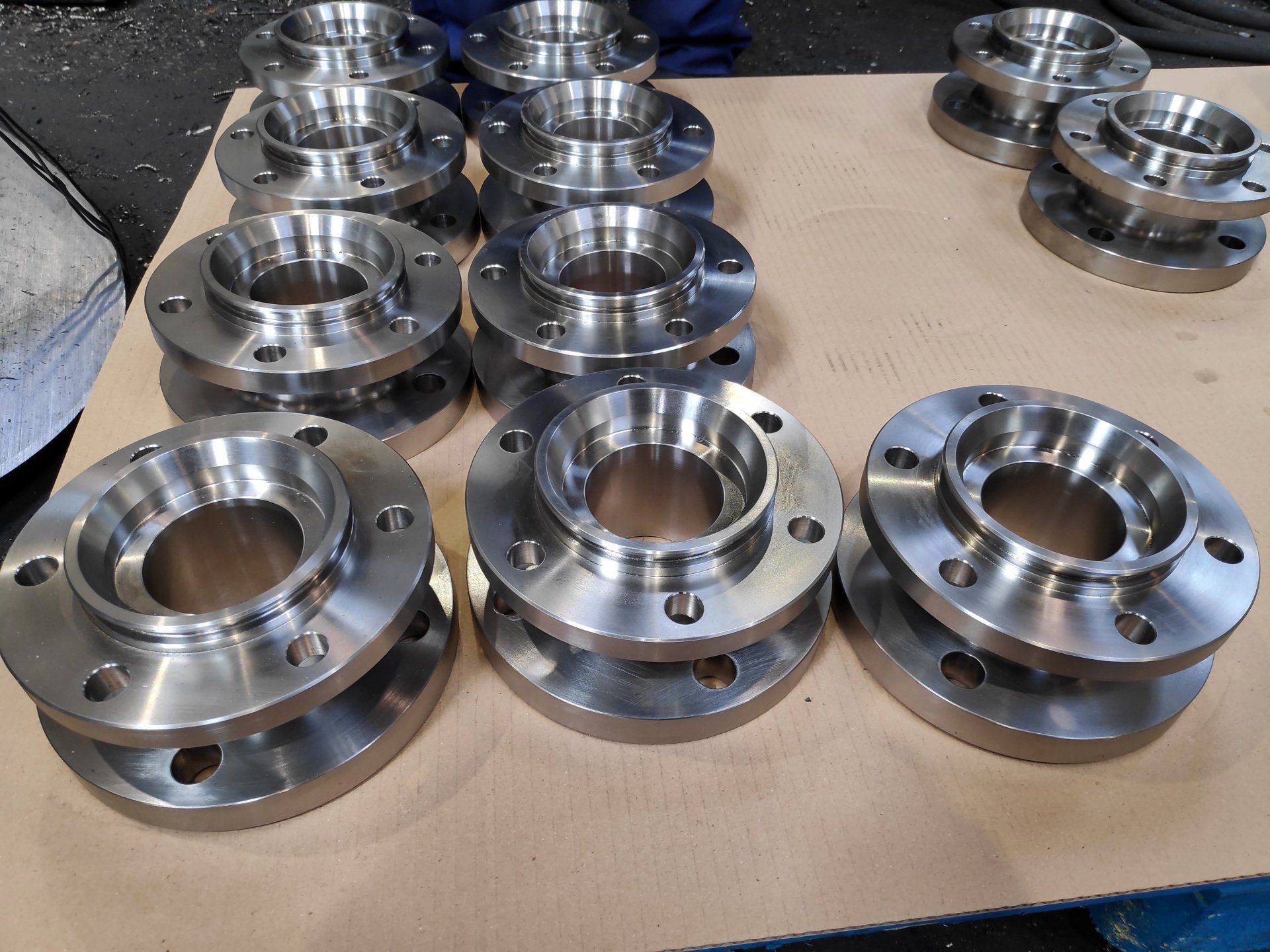 Lote de bridas industriales mecanizadas en CNC con alojamiento interior y taladros de fijación, fabricación en serie.