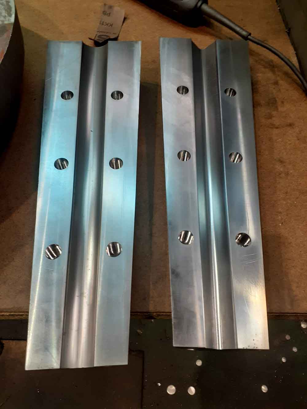 Placas metálicas mecanizadas en CNC con ranura central y orificios de fijación, componentes industriales de alta precisión.