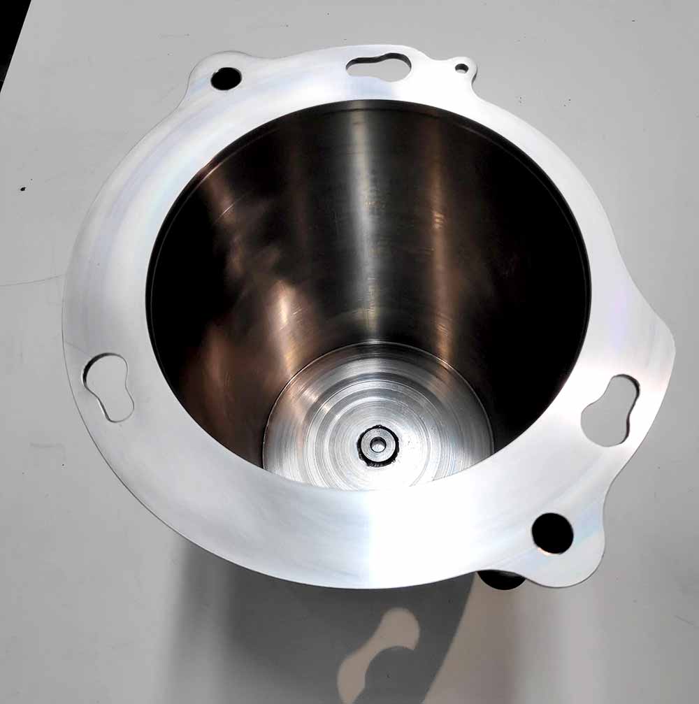 Cuerpo metálico mecanizado en CNC con cavidad cilíndrica y brida de fijación, componente industrial de alta precisión.