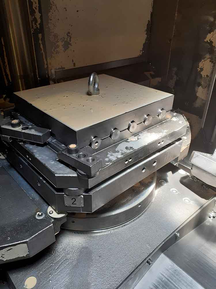 Utillaje de sujeción mecanizado montado sobre mesa giratoria de máquina CNC para operaciones de mecanizado de alta precisión.