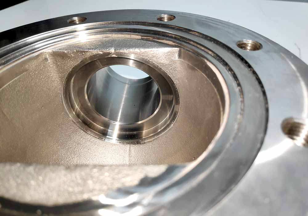 Detalle interior de cuerpo de bomba mecanizado en CNC con alojamiento central y superficie de precisión industrial.