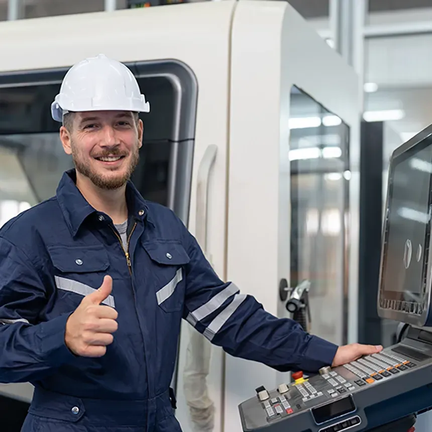 Operador de mecanizado CNC con casco de seguridad junto a centro de mecanizado industrial, mostrando aprobación del proceso de producción.