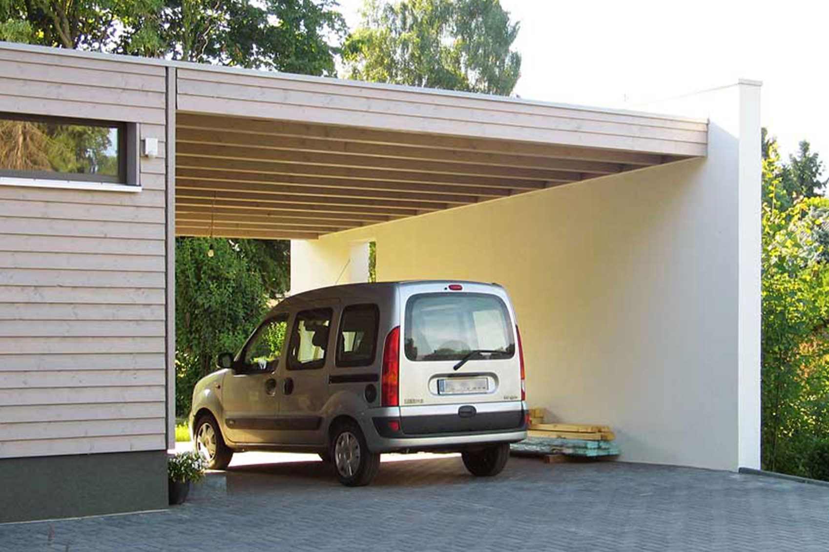 Ein Auto steht in einer offenen Garage neben einem Haus