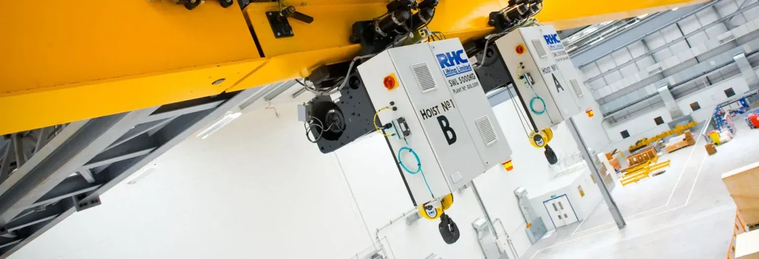 2 hoists positioned on a beam above a factory unit