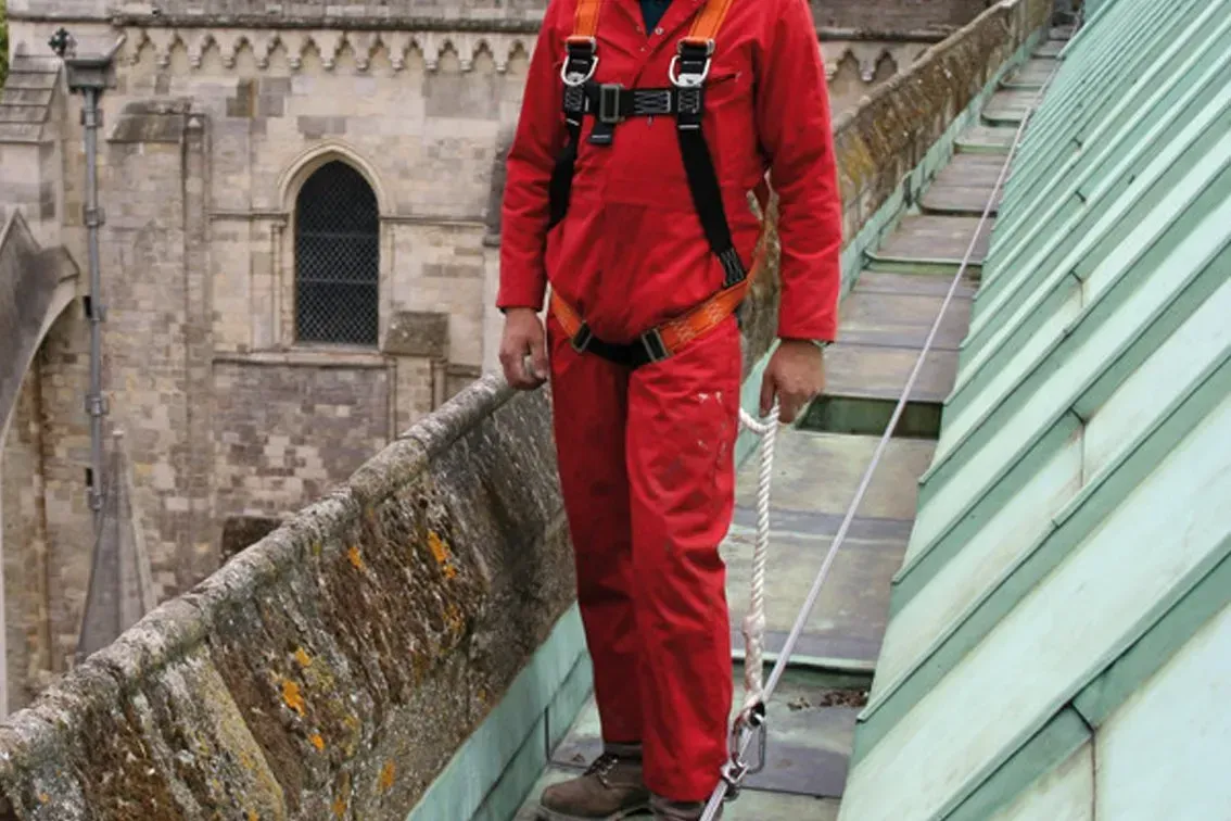 A person on top of a roof wearing a safety harness