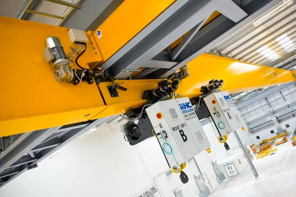 Two cranes latched onto a lifting beam