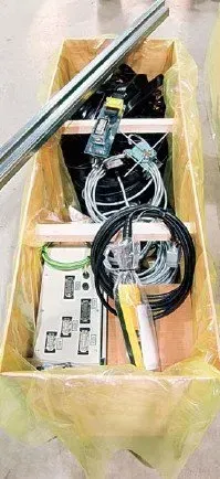 The inside of an open wooden pallet box, showing wires and other crane kit equipment