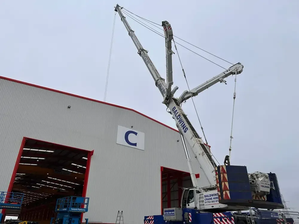 An outside view of a mobile crane lifting inside of a building
