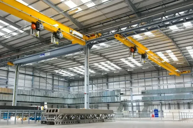 A wide angle view of a latching crane system, spanning across the ceiling of a factory