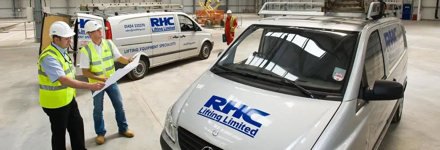 2 RHC Lifting engineers standing next to an RHC van, looking at paperwork