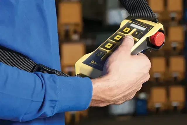 An LK NEO pushbutton remote being held by a shoulder strap and operated