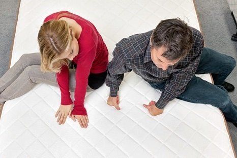 A couple looking at and trying a mattress