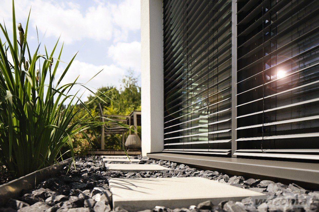 Detailansicht Vorbau Raffstore, halb geöffnete Lamellen mit Sonnenlichteinfall, Ansicht von außen