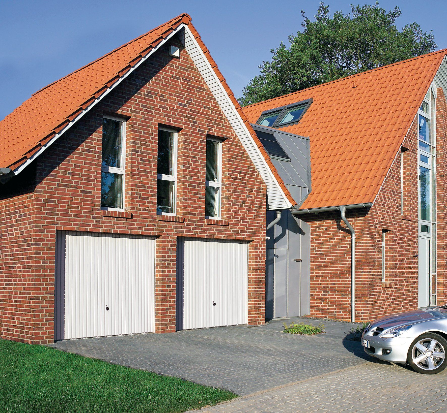 zwei weiße Garagentore in einem Backsteinhaus, Ansicht von vorne, Tore geschlossen